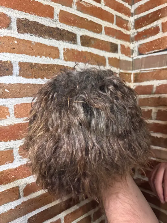 Goat Fur Papakha held in a hand: long curly light brown fur seen from above
