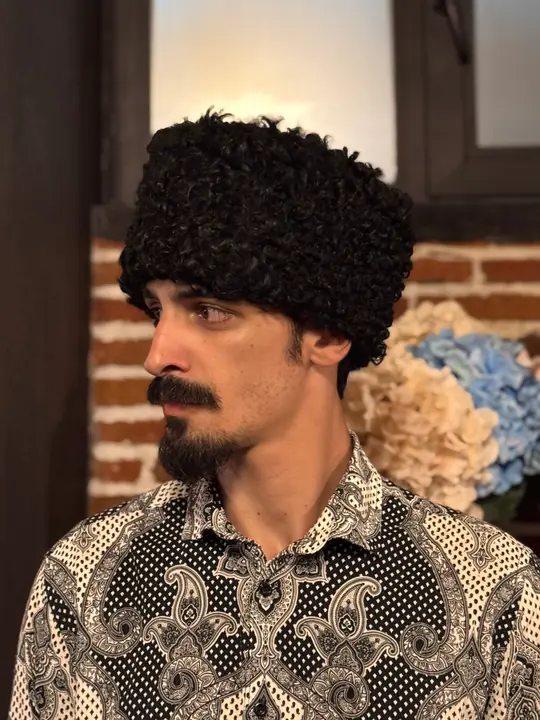 Karakul Papakha in profile, facing left: the straight sides and flat top of short black curls