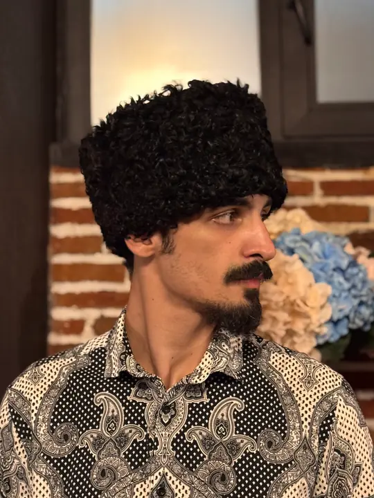 Karakul Papakha in profile, facing right: a neat, tall cylinder of tight black curls
