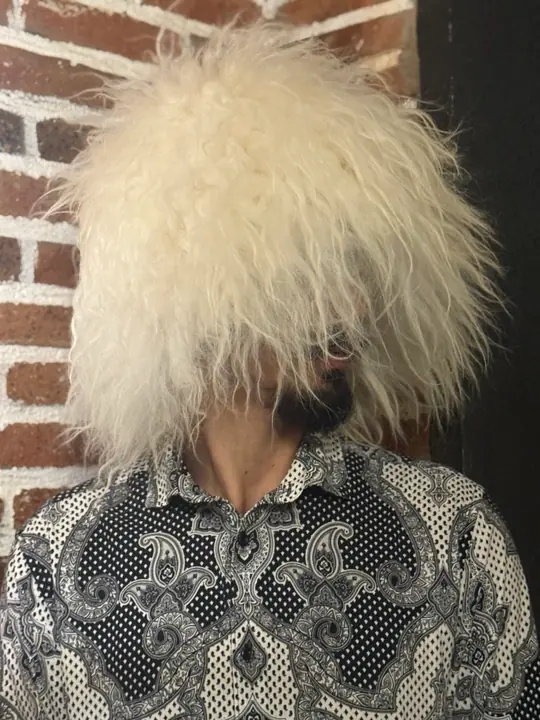 Very White Sheepskin Papakha, front view with the head turned slightly: straight wool hanging past the eyes