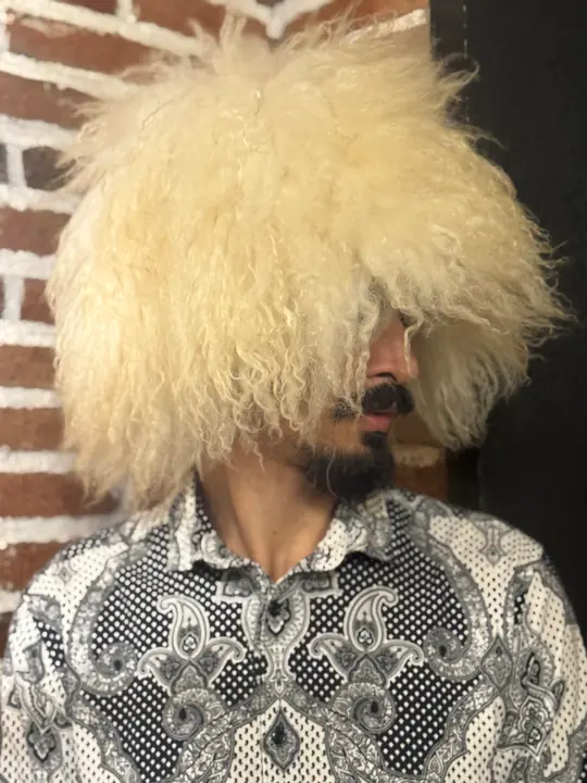 White Sheepskin Papakha, three-quarter view from the left: long wavy cream-white wool falling over one side of the face