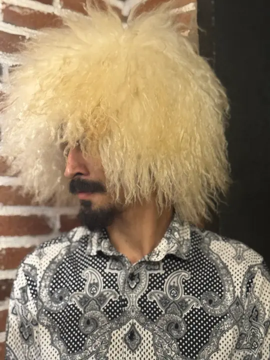 White Sheepskin Papakha in profile, facing left: the long wavy wool stands out wide around the crown