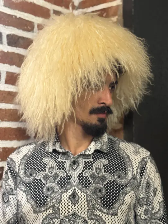 White Sheepskin Papakha in profile, facing right and looking down: a broad, rounded crown of wavy wool