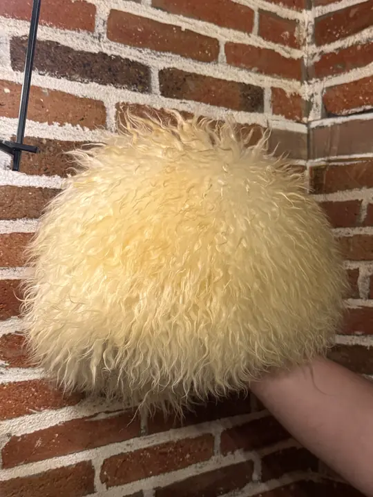 White Sheepskin Papakha Special held in a hand: the rounded dome of creamy white curly wool from the side